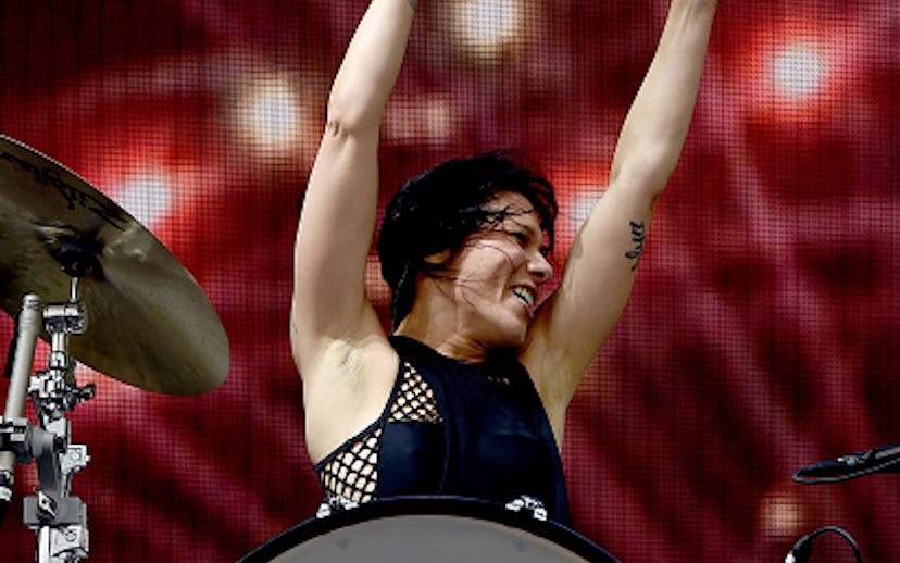 A female drummer performing on stage with her hands up in the air