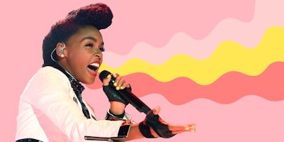Janelle Monáe singing in front of the pink background while wearing a white jacket
