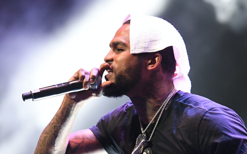 Dave East on stage holding a microphone and a towel on his head