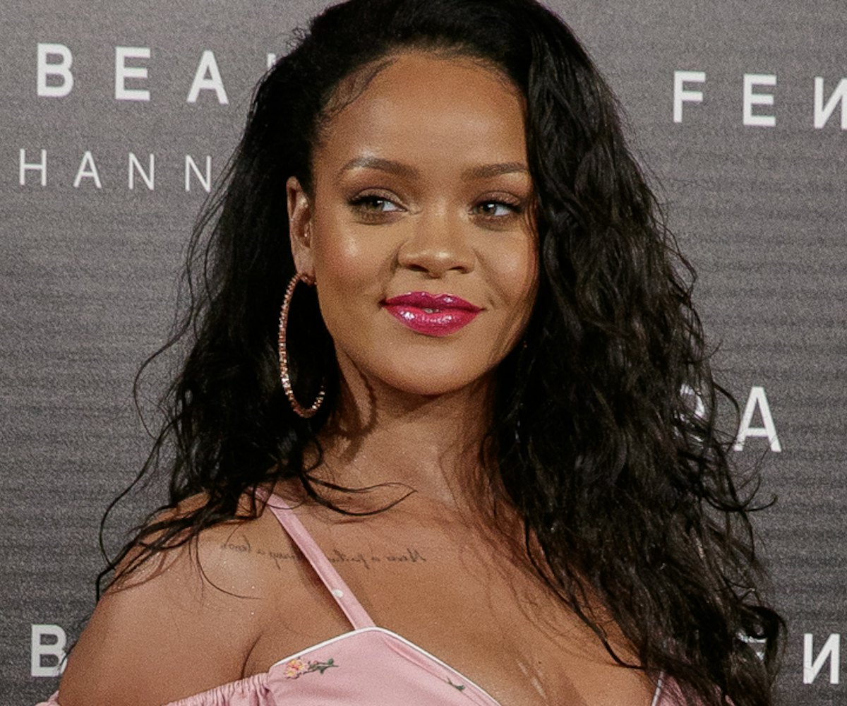 Rihanna in a pink floral dress with large hoop earrings at a Fenty Beauty event