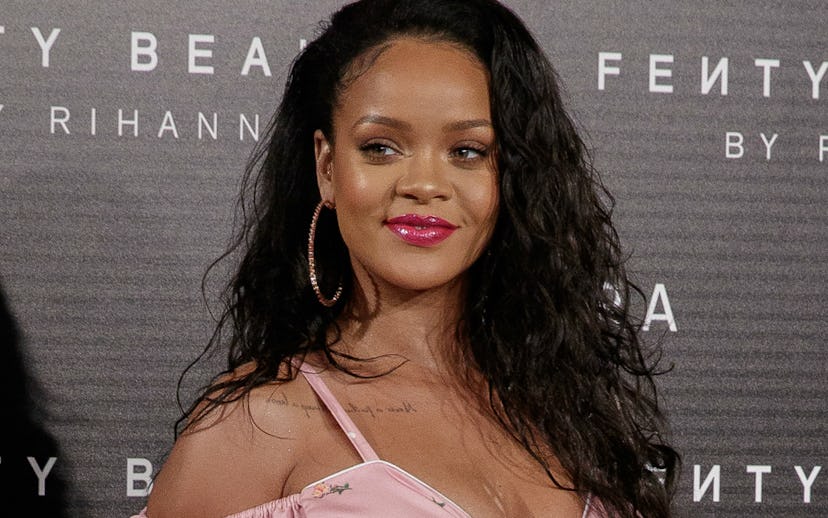 Rihanna in a pink floral dress with large hoop earrings at a Fenty Beauty event