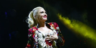 Gwen Stefani on stage in a multicolored blazer, sporting a high ponytail. 
