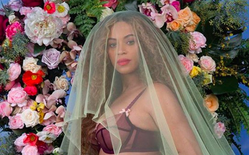 Beyonce kneeling and holding her pregnant stomach in blue denim shorts with a yellow tulle veil and ...