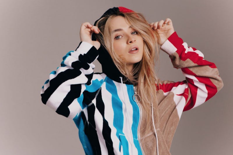 Sabrina Carpenter in a striped multi-colored hoodie with blonde hair