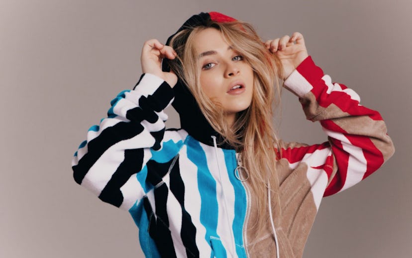 Sabrina Carpenter in a striped multi-colored hoodie with blonde hair