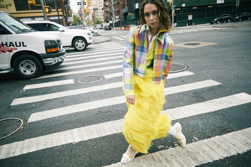 A brunette woman in a pastel multi-colored print shirt, pastel multi-colored checked jacket and a lo...