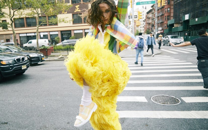 A brunette woman wearing a pastel multi-colored shirt, pastel multi-colored checked jacket, and a lo...