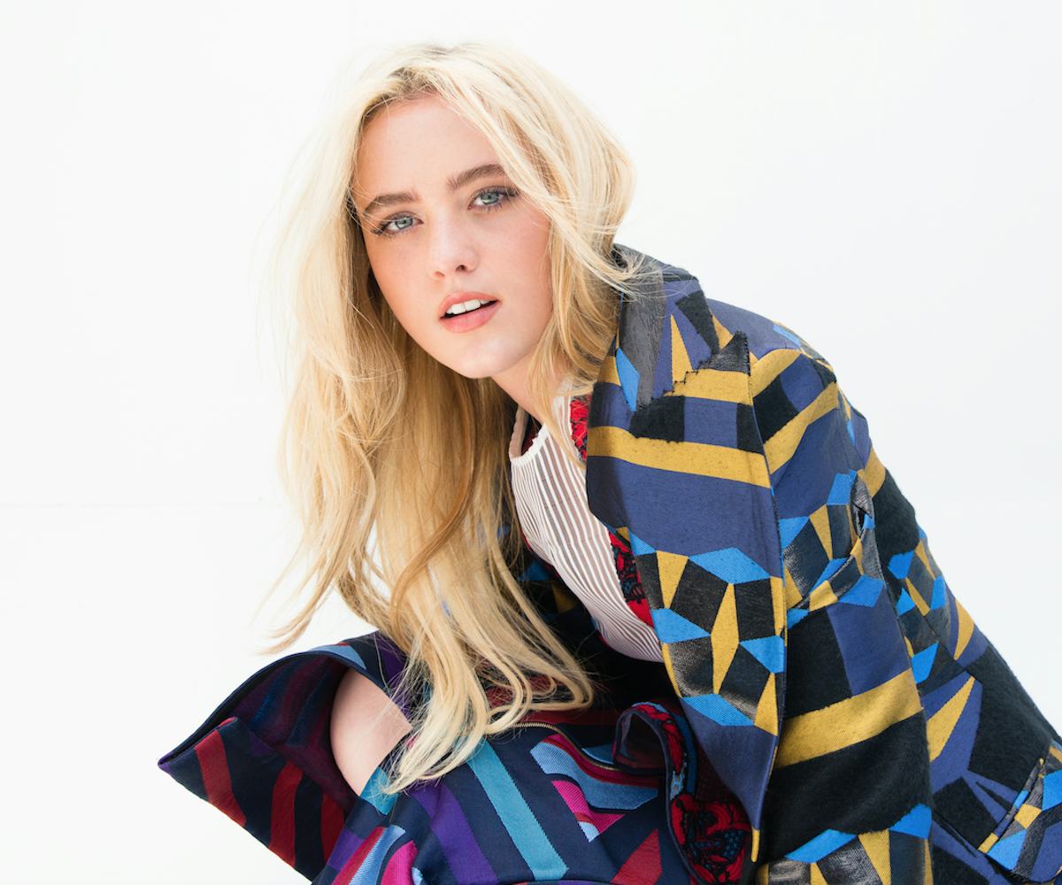 Kathryn Newton wearing a blue coat with colorful stripes 