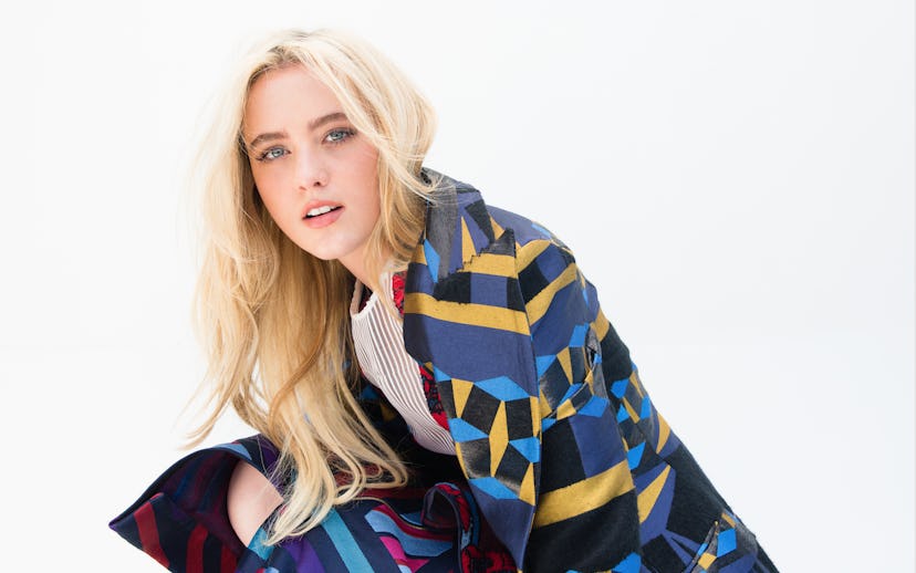 Kathryn Newton wearing a blue coat with colorful stripes 