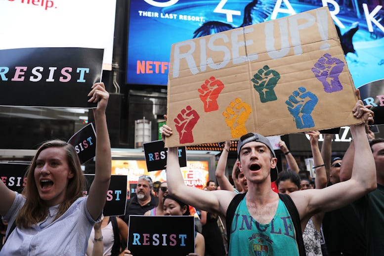 A group of people holding posters with the writing 'Resist' against Trump's Transgender Ban