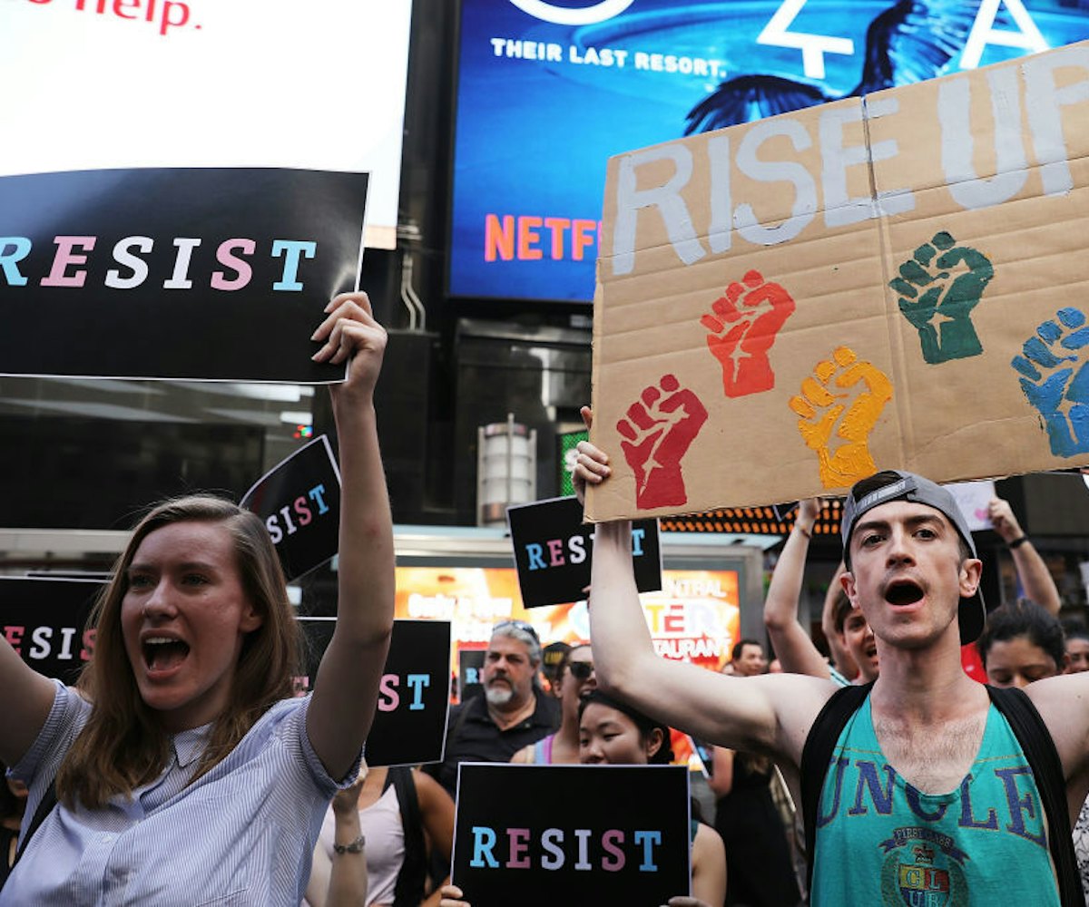 A group of people holding posters with the writing 'Resist' against Trump's Transgender Ban