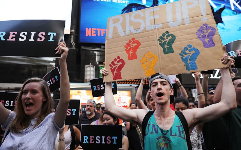 A group of people holding posters with the writing 'Resist' against Trump's Transgender Ban