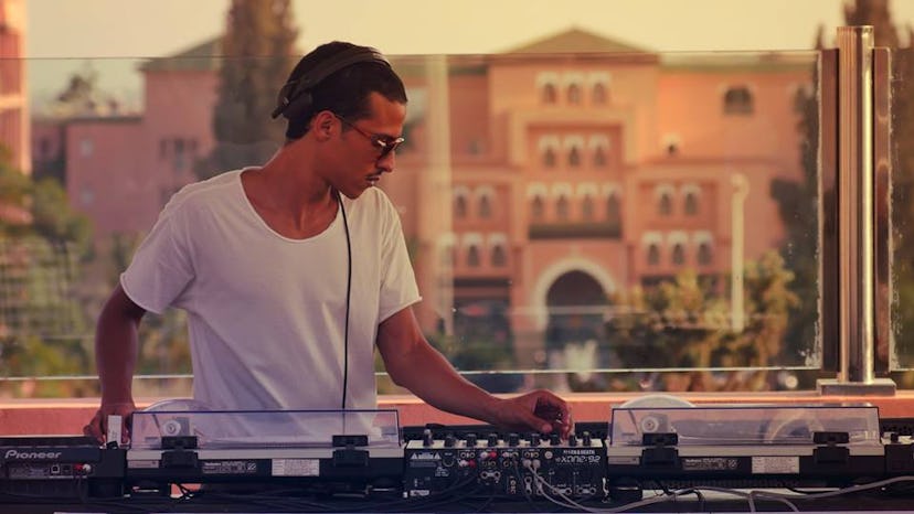 Moroccan DJ Polyswitch performing while wearing a white shirt and sunglasses