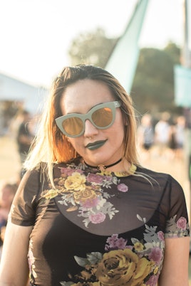 Girl posing while wearing matching green sunglasses and a green lipstick 