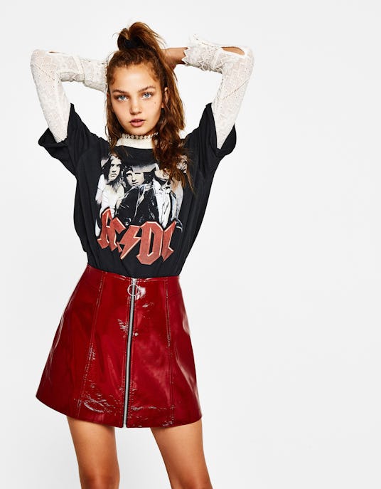 Brunette model in an AC/DC shirt and in a Bershka maroon faux leather mini-skirt