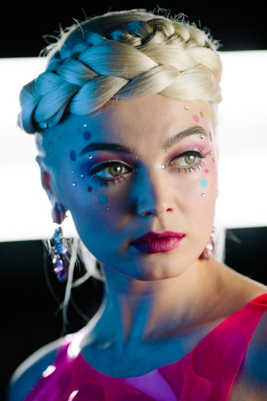 Neon Demon showing off the eyeliner, long eyelashes, pink lipstick, and glitter and stickers around ...
