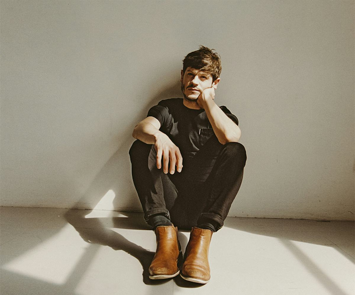 The Breakout actor Iwan Rheon posing while sitting on white floor