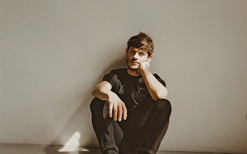 The Breakout actor Iwan Rheon posing while sitting on white floor