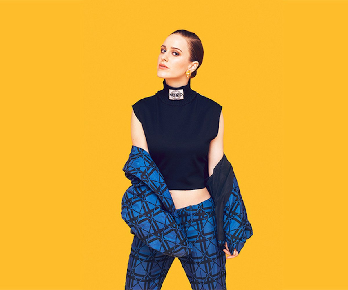Rachel Brosnahan posing in a black sleeveless turtleneck and matching blue pants and jacket