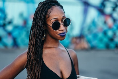 A girl with braided hair, round sunglasses, and blue lipstick
