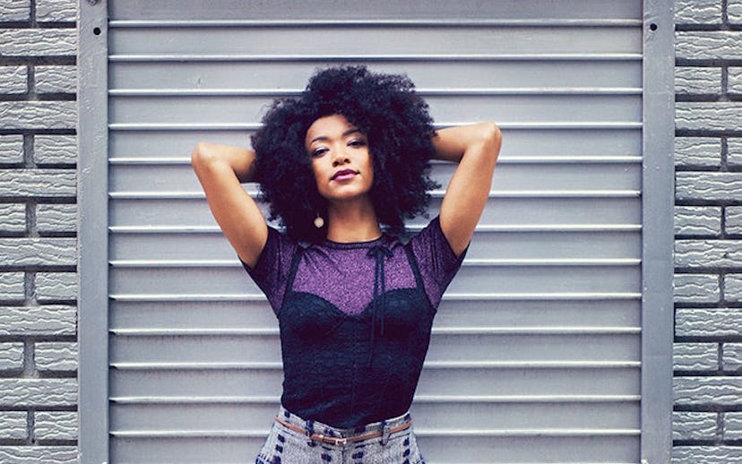 Sonequa Martin-Green, wearing a corset over a purple T-shirt, paired with grey plaid pants.