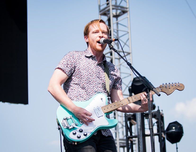 Kevin Devine on stage singing and playing an electric guitar 