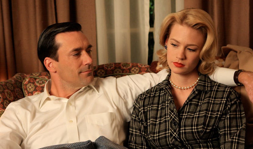 Jon Hamm hugging and looking at January Jones on a couch in a scene from Mad Men