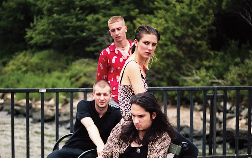 Band members of Wolf Alice posing on a bench and all looking into the distance