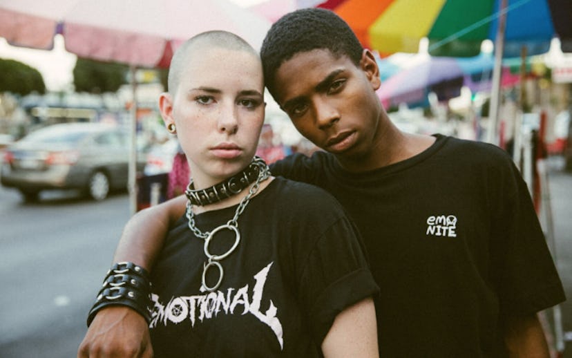 Two people wearing chains and black shirts with "Emotinal" and "Emo Nite" text signs