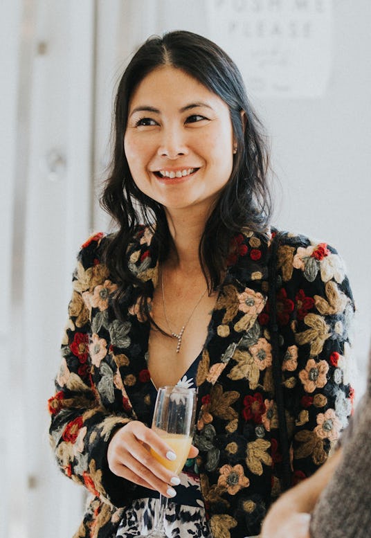 Minh Le drinking champagne in a black floral blazer