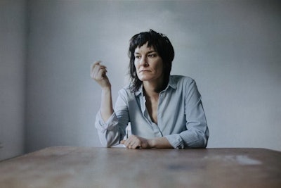 Jen Cloher, an Australian singer sitting on a grey background 