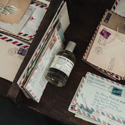 A bottle of Mousse de Chen perfume between letters from Le Labo’s City Exclusives 