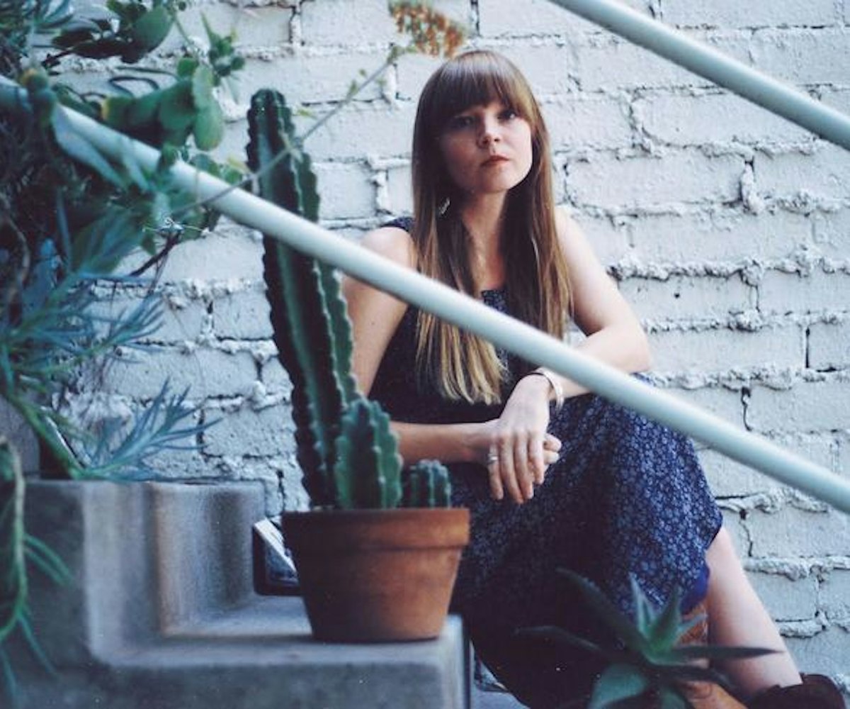 Courtney Marie Andrews posing on the stairs behind a cactus.