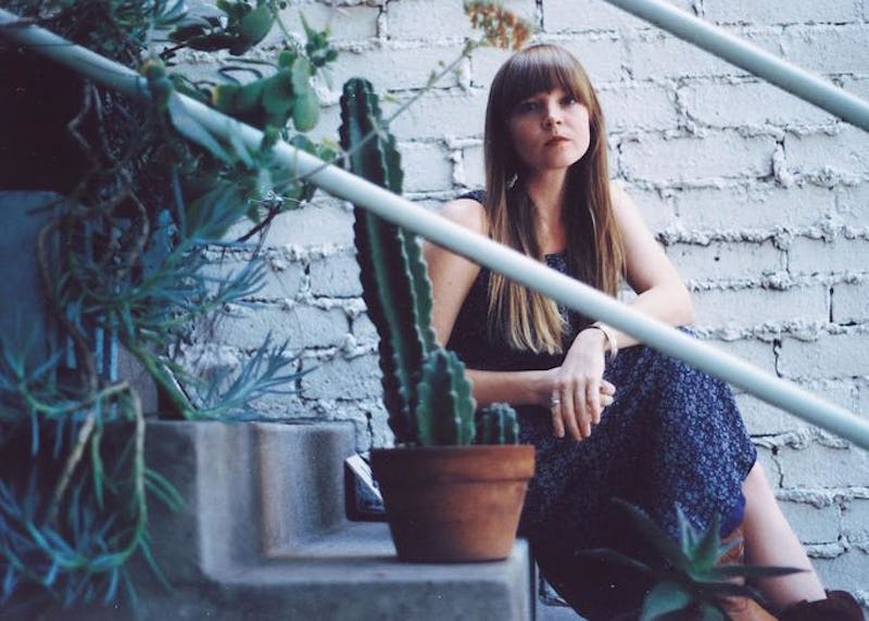 Courtney Marie Andrews posing on the stairs behind a cactus.