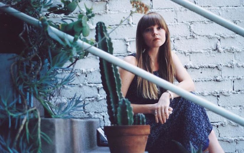 Courtney Marie Andrews posing on the stairs behind a cactus.