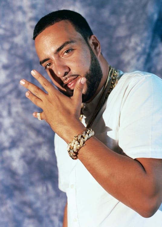 French Montana posing in a white button down shirt with gold jewelry on his neck and left hand