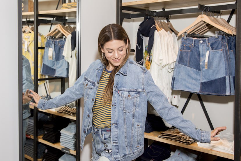 A girl trying on a Levi's denim jacket and looking very pleased