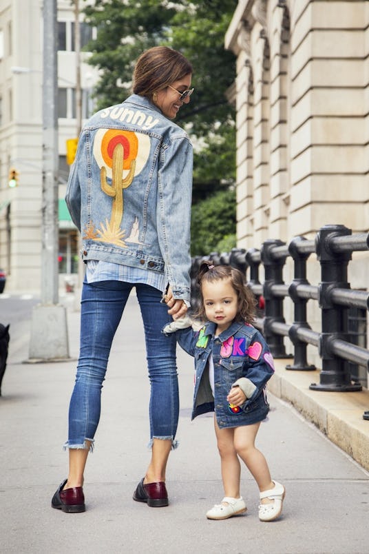 A woman and a little girl wearing matching Levi's denim jackets with stickers on the back having the...