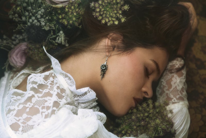 Kt Ferris lying with her head down in a white dress and flowers in her hair