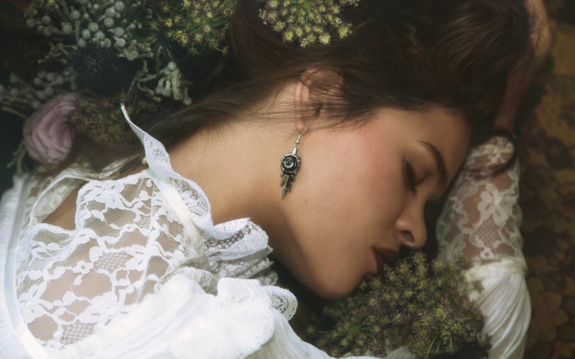 Kt Ferris lying with her head down in a white dress and flowers in her hair