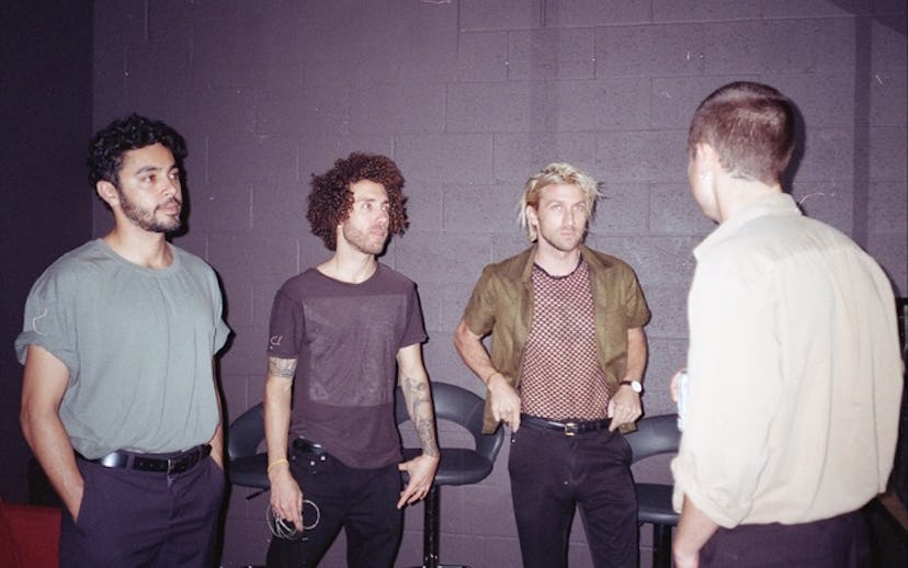 Hany Zayan, Chris Hess, and Adam Winn are facing a man in a white shirt in front of a gray wall