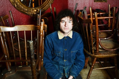 Ryley Walker  sitting in a closed bar with chairs on the tables