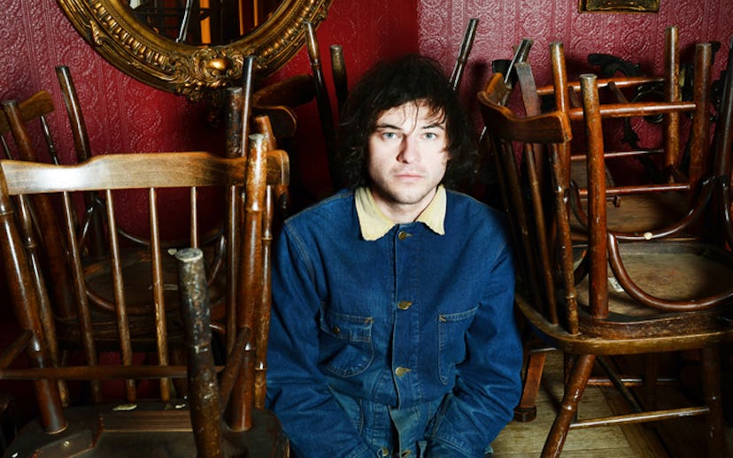 Ryley Walker sitting in a closed bar with chairs on the tables