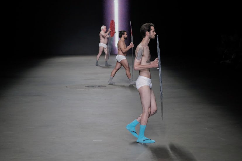 Three male models in white underwear holding shields