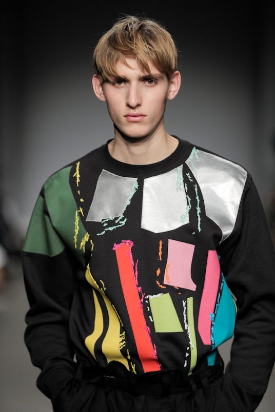 A male model in a black sweatshirt with different-colored shapes on it