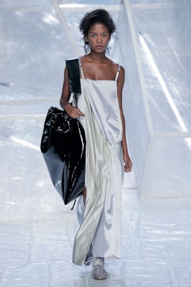 A female model in a gray long dress carying a big black bag