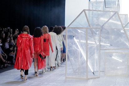 A fashion show showing all red and all white outfits next to see-trough boxes