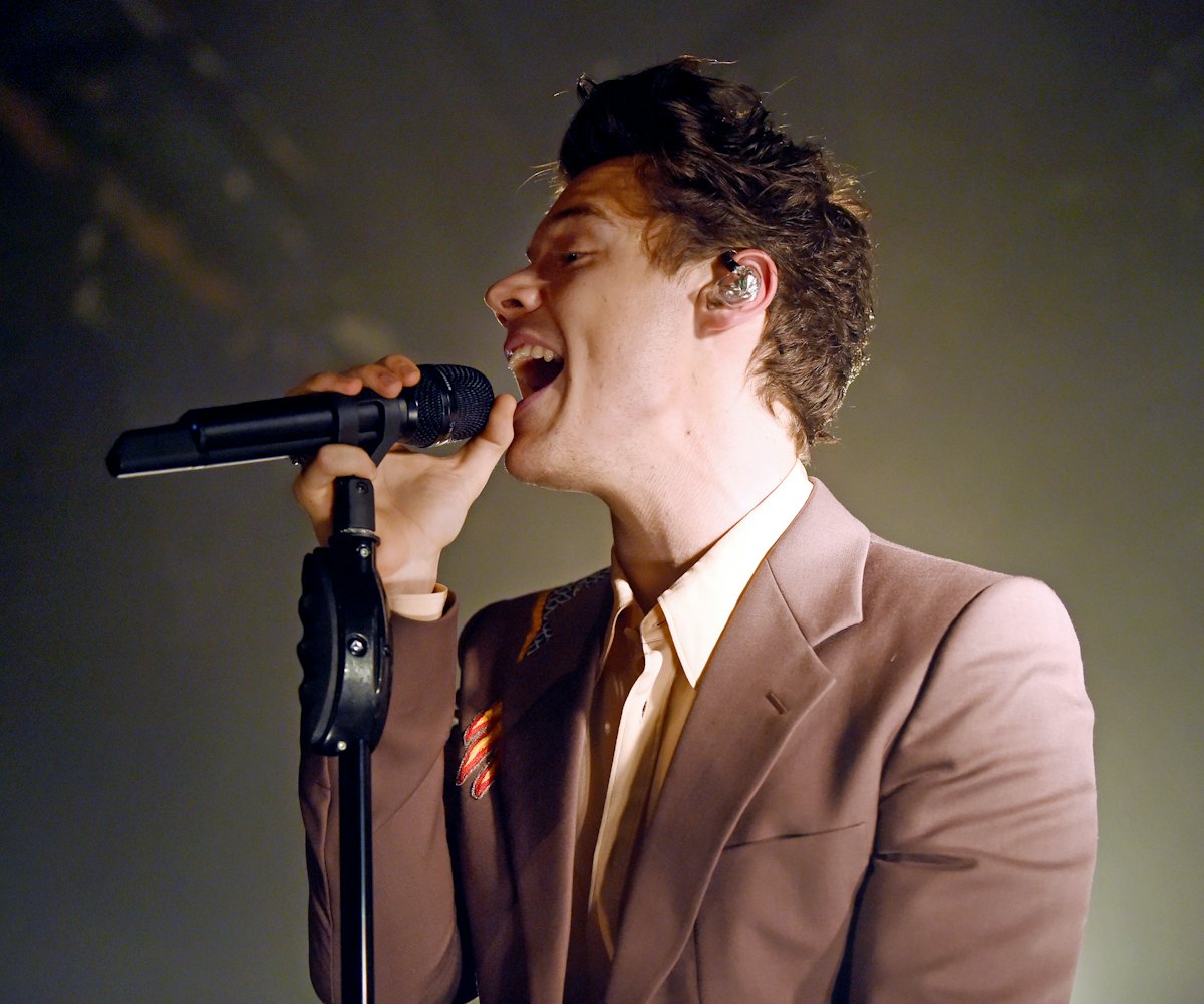 Harry Styles singing in a simple brown suit