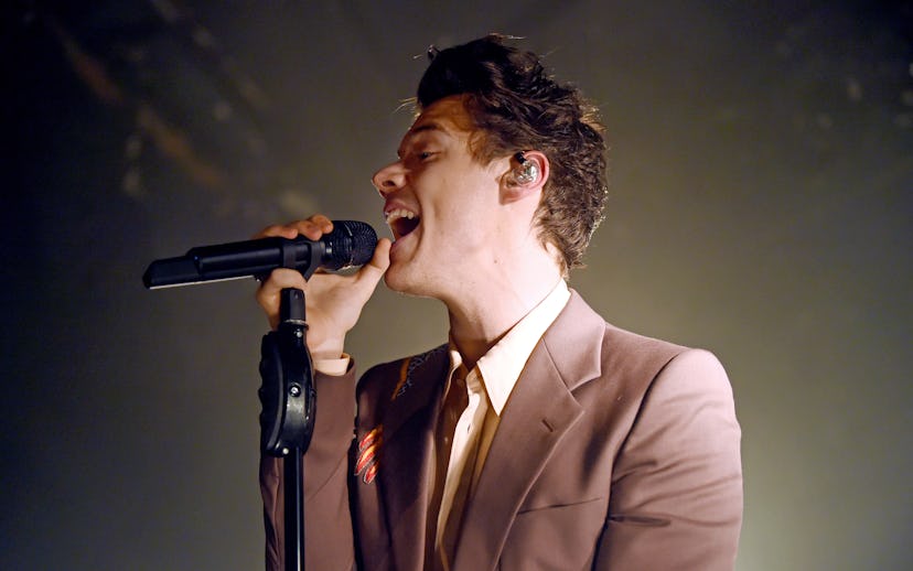 Harry Styles singing in a simple brown suit