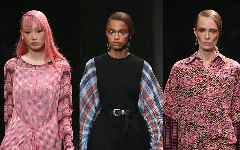 Three models walking during a fashion show, two of them wearing pink dresses and one of them wearing...